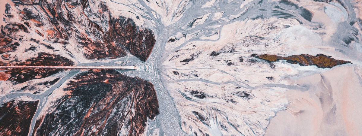 Aerial view of a glacial river delta with intricate water patterns and sediment.