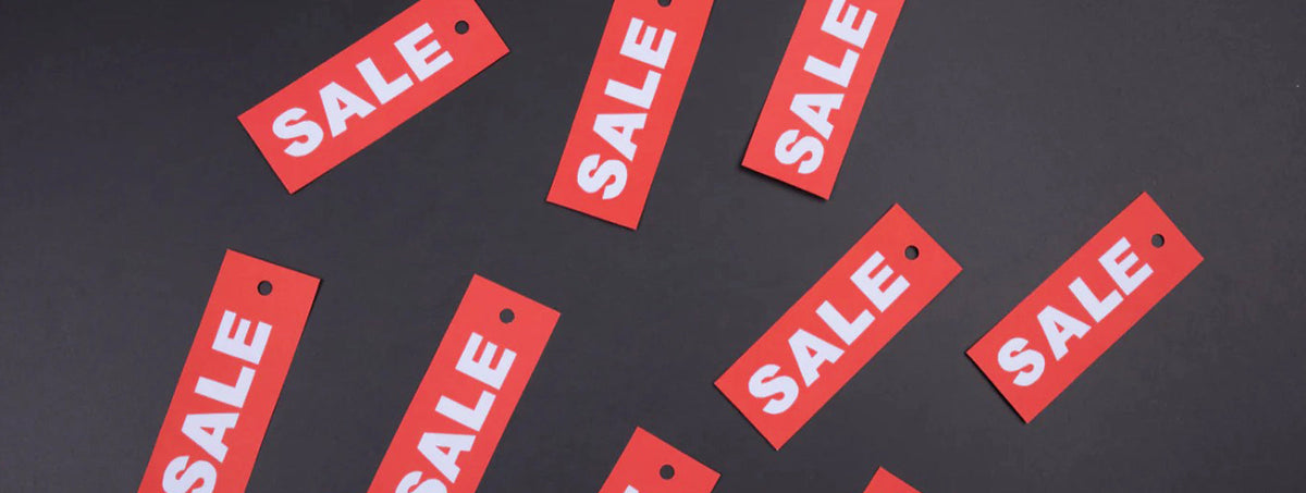 Red sale tags scattered on a dark gray background.